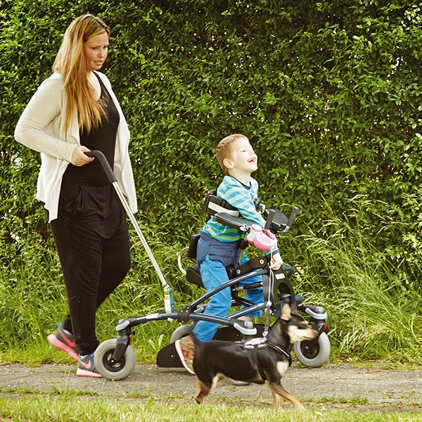 Boy and mother walking while using the The Etac/R82 Mustang pediatric folding gait trainer