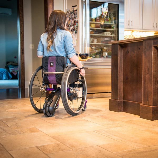 Max Mobility SmartDrive MX2 Wheelchair Power Assist being used by girl in kitchen setting