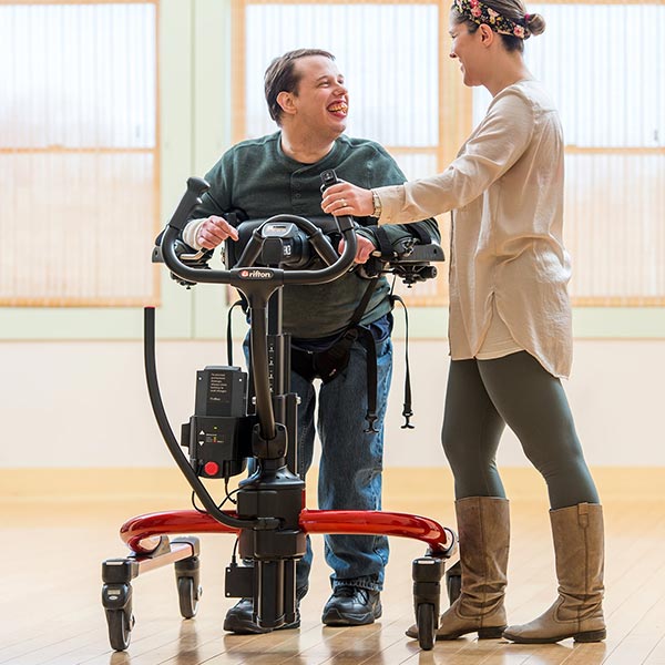 Adult male using the Rifton E-Pacer Adult Gait Trainer working with female caregiver