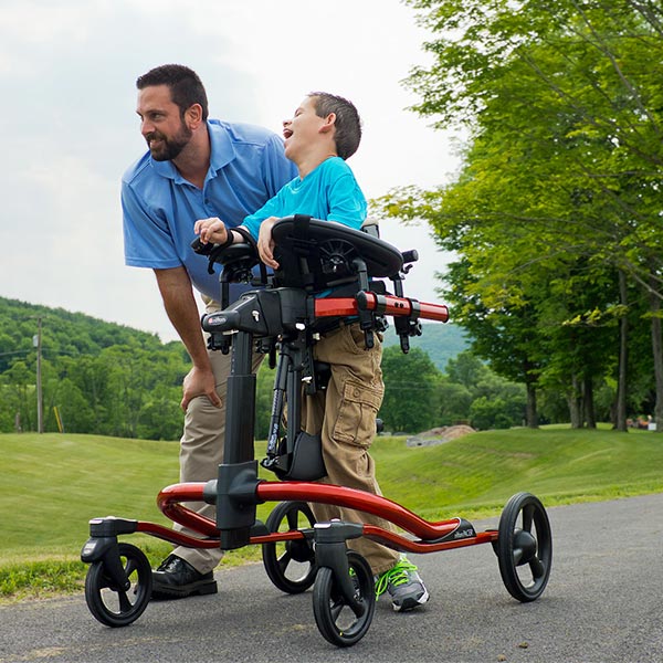 Male caregiver and young boy with disabilities using the Rifton Pacer gait trainer