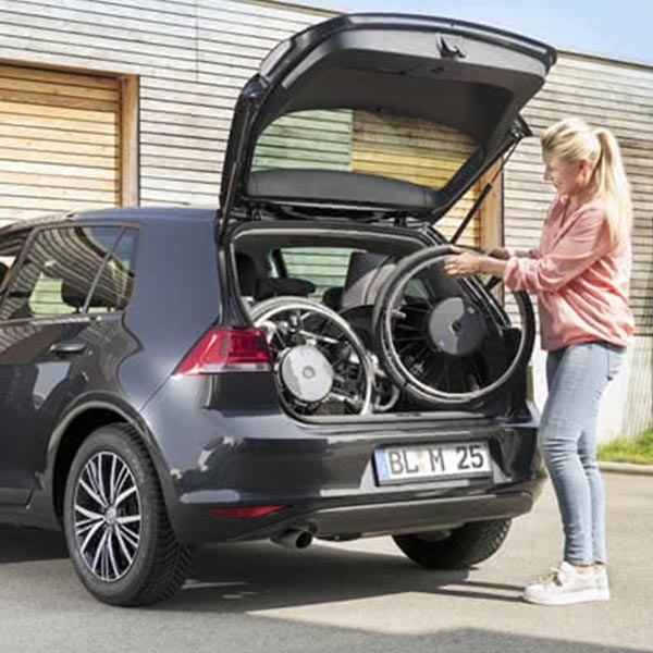Wheelchair with Alber e-motion power assist system attached and easily fitting into the trunk of a car.