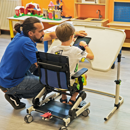 Child using Grillo Chair with tray using a tablet